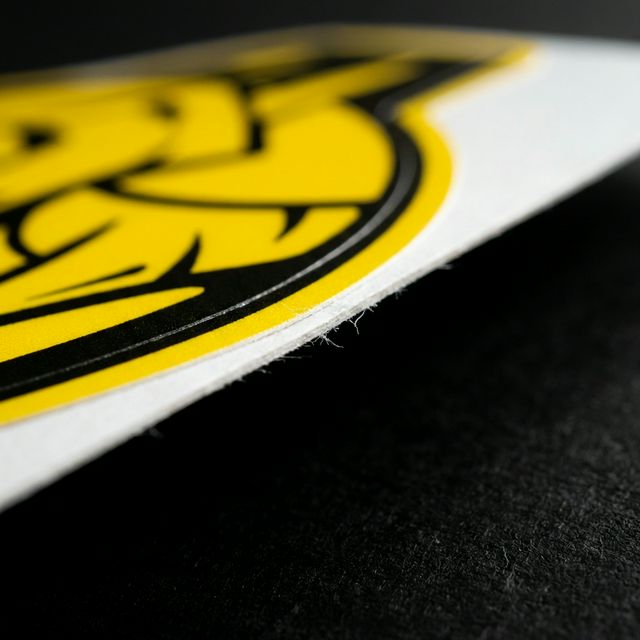 Un acercamiento extremo al borde de un sticker Die Cut mostrando la navaja de corte trazando el contorno.