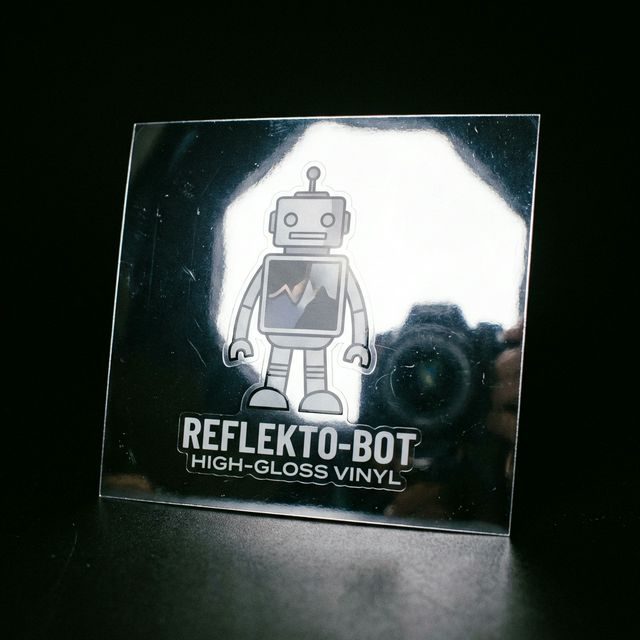 Sticker con acabado brillante reflejando una luz fuerte, demostrando su textura súper lisa y plastica.